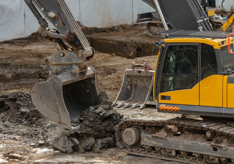 yellow and black excavator on brown soil